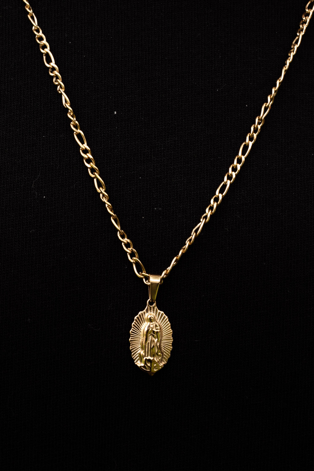Cadena con dije de Virgen sobre fondo negro
